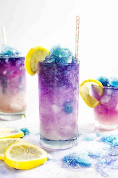 three glasses filled with colorful liquid and lemon slices