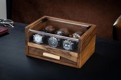 three watches are in a wooden box on a table next to a pair of glasses