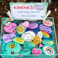 a basket filled with lots of rocks covered in different colors and sayings on them