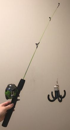 a person holding a fishing rod with two hooks attached to the wall and an umbrella hanging from the ceiling