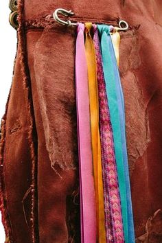 the back of a brown jacket with multi colored ribbons hanging from it's side