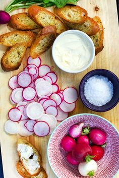 a cutting board topped with bread, radishes and other food items on top of it