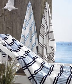 towels hanging on the side of a wooden wall next to a potted plant and an umbrella