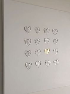 a white wall with many hearts cut out of it and a gold heart in the middle