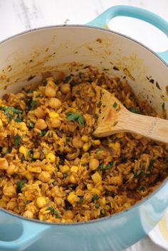 a blue pot filled with food and a wooden spoon