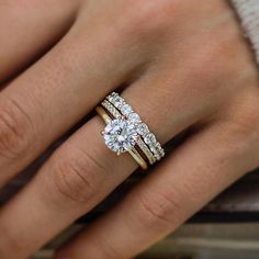 a woman's hand with two wedding rings on her left and the other hand holding an engagement ring