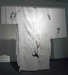 two pieces of white paper with drawings on them hanging from the side of a wall