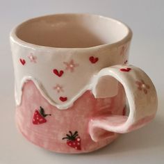 a pink and white coffee cup with strawberries on it