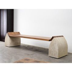 a concrete bench sitting on top of a cement floor next to a white wall and wooden door