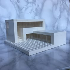 a lego model of a house made out of white plastic bricks on a marble countertop