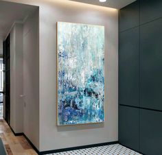 an abstract painting hangs on the wall next to a tiled floor in a modern hallway