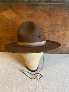 Vintage Stratton Boy Scout Military Campaign Hat Drill Sergeant Instructor Hat/Patrol Mountie Ranger Hat Smokey Bear This hat features a 4 dented crown, a brown grosgrain hat band and button tied neck strap.  Condition as shown.   Size 7 & measures approx. 22 1/4" inside hat band. The hat is approx. 12 1/2" by 14 1/2" by 5 1/2" tall. Drill Sergeant, Smokey Bear, Boy Scout, Hat Band, Boy Scouts, Neck Strap, 1960s Vintage, Caps Hats, Accessories Hats