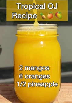 a jar filled with orange juice sitting on top of a wooden table next to a sign that says tropical oj recipe