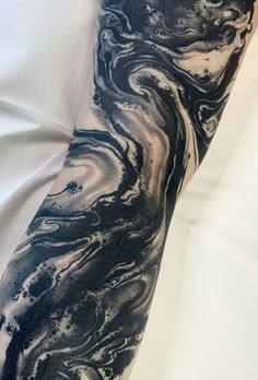 a man's arm covered in black and white marbled ink, with his hand on top of the arm