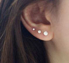 a close up of a person's ear with three small white stones on it