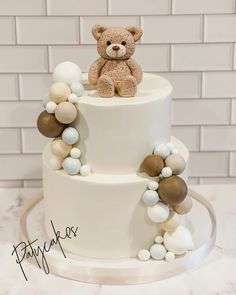 a teddy bear is sitting on top of a white tiered cake with multi - colored balls