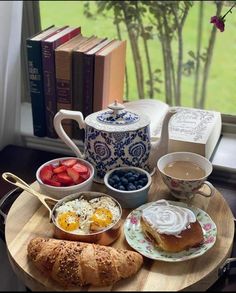 the breakfast is ready to be eaten on the tray by the window sill with books