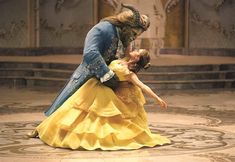 a man and woman dressed as beast and snow white dance in front of a stage