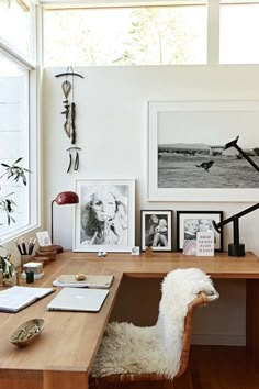 a wooden desk topped with a white chair and lots of pictures on the wall above it