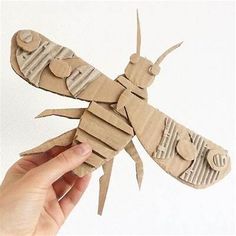 a person holding up a paper cut out of a bug with its wings folded down