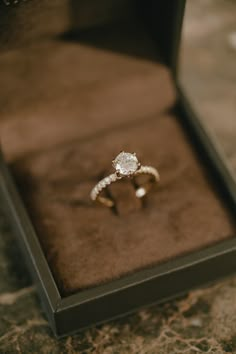 an engagement ring in a box on the ground