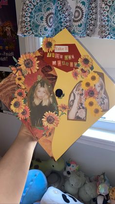 a person holding up an umbrella with sunflowers and pictures on it in front of a window