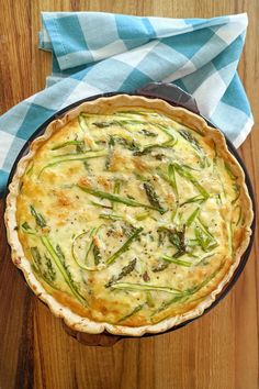 a quiche with asparagus and cheese in a pie pan on a wooden table