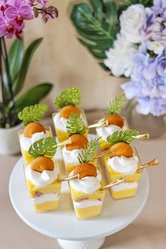 small desserts are arranged on a white plate with purple flowers in the back ground