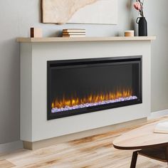 an electric fireplace in a living room with wood flooring and wall mounted art on the wall