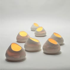 five white rocks with yellow lights on them sitting in the middle of a plain surface