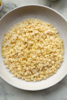 a white bowl filled with rice on top of a table next to other food items