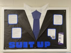 a bulletin board with some blue and white items on it that says suit up in front of a man's necktie