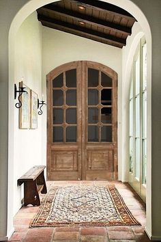 an arched doorway with two wooden doors and a rug on the floor in front of it