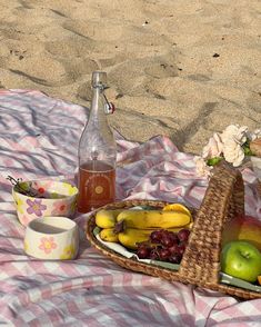 a picnic basket with apples, bananas, and other fruit on it next to a bottle of water