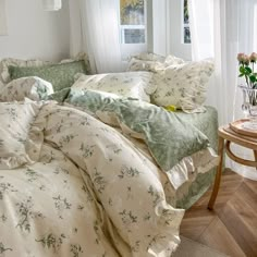 an unmade bed with green and white comforter in a bedroom next to a window