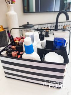 Black and white striped toiletry container filled with lip color, facial cleanser, sunscrene, serums and cotton rounds.