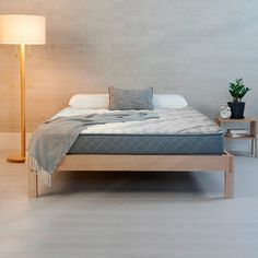 a bed sitting in the middle of a room next to a lamp and a table