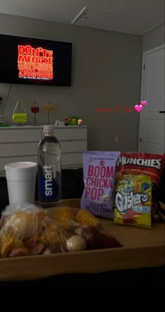 food and drink on a table in front of a flat screen tv with neon signs above it