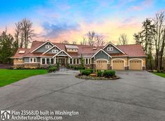 a large home in the middle of a driveway with lots of grass and trees around it