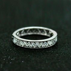 a white gold wedding band with diamonds on it's sides and an intricate design in the middle