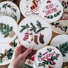 someone is holding up some christmas ornaments in front of their embroideryed cross - stitch hoop