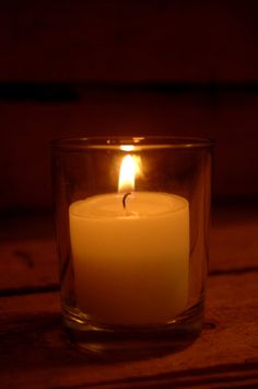 a lit candle sitting in a glass container