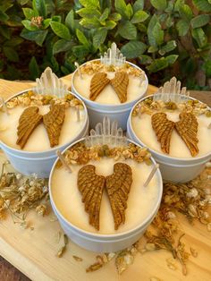 four desserts in bowls on a wooden table with leaves and flowers around the bowl