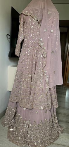 A beautiful soft onion, pink colour Lehenga with full Ghera /flare  and cancan to give complete wedding  wear look. The colour of this is so well, suitable for bride, bridesmaids mother of the bride or everyone. The work is done in dull Gold and mirror work, which gives it a perfect soft bling and not too shiny to make it very alluring and elite. The top of the Lehenga is a full Gera Anarkali, which has worked all over front and back and Tailor to fit size large US size 12 The dupatta also has border on all four sites and butties all over. One can also wear this outfit in another form using the  Anarkali top with a simple pants and dupatta that making it a Anarkali suit.  So, when you buy this Lehenga, it is like buying two exclusive wedding wear dresses. Pink Reception Dress With Cutdana Details, Pink Dress With Cutdana For Reception, Pink Pallu Dress For Reception, Pink Floor-length Sharara With Pallu, Pink Floor-length Sharara, Elegant Pink Dress With Cutdana Details, Pink Gown With Cutdana In Saree Shape, Pink Gown With Cutdana Details In Saree Shape, Pink Floor-length Sharara For Navratri