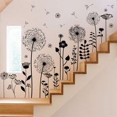 a stair case with a bunch of dandelions painted on the wall next to it