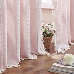 pink curtains with white trim and tassels in front of a potted plant