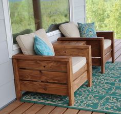 two wooden chairs sitting on top of a porch next to a green rug and window