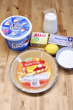 ingredients to make lemonade cake sitting on a wooden table next to a container of yogurt