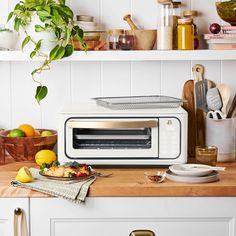 a toaster oven sitting on top of a kitchen counter next to fruit and utensils