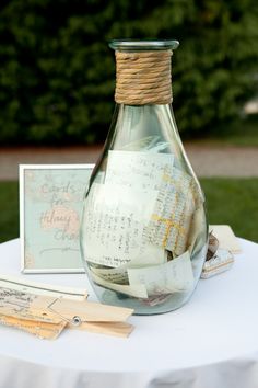 a glass bottle filled with notes sitting on top of a white tablecloth covered table